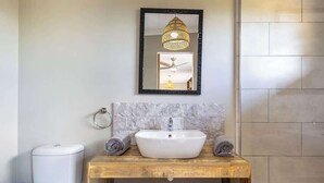 A bathroom with a wooden vanity, white sink, and a mirror with a black frame.