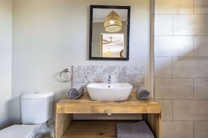 Une salle de bain avec un meuble-lavabo en bois, un lavabo blanc et un miroir avec un cadre noir.