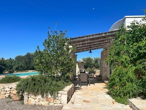 Un sentiero in pietra conduce a un patio con arredi da esterno, una piscina e una pergola.