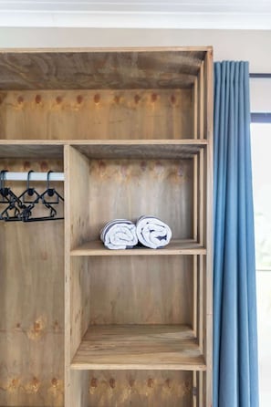 Ein Holzregal mit zwei Ablagen, eine davon mit aufgerollten Gegenständen.
