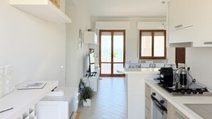 A modern kitchen with white cabinetry, a central island, and a view to the outside. - P095 - Porto Recanati, new three-room apartment  (Porto Recanati)