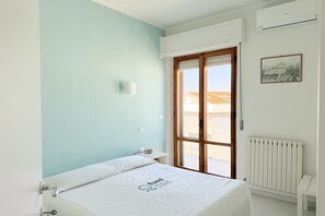 A bedroom with a bed, a nightstand, a radiator, and a window with a view. - P095 - Porto Recanati, new three-room apartment  (Porto Recanati)
