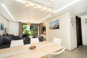 Ein modernes Wohnzimmer mit Esstisch, Sofa und Pendelleuchten.