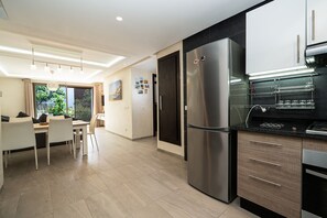 Eine moderne Küche mit einem Edelstahlkühlschrank, einem eingebauten Backofen und einem Essbereich mit Tisch und Stühlen.