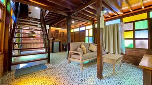 A room with a wooden ceiling, a sofa, a small table, a staircase, and a brick wall. - Golden Chenang Village (Langkawi)