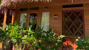 A wooden building with a thatched roof, large windows, and potted plants in front. - Golden Chenang Village (Langkawi)