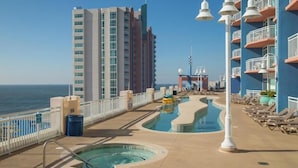 Un área de piscina con un jacuzzi, sillas de descanso y vistas al océano.