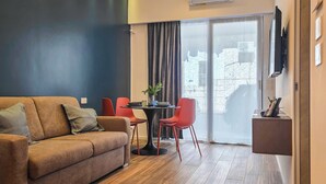 A modern living room with a sofa, red chairs, a small table, and a TV mounted on the wall. - Grigio Perla Suites  (Manfredonia)