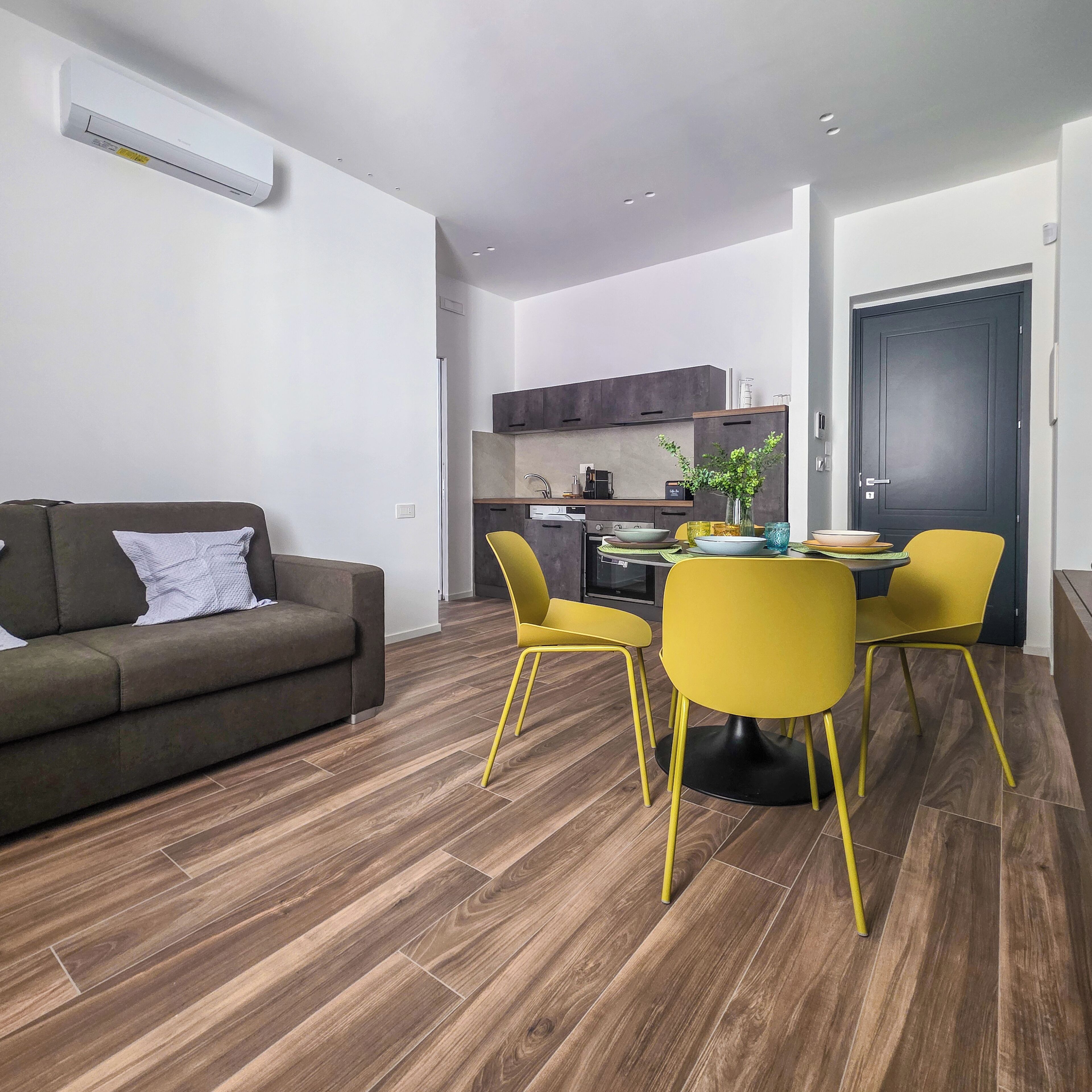 Un salon moderne avec un canapé, des fauteuils jaunes et une table à manger.