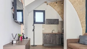 A modern apartment with a kitchen, a living area, and a stone archway. - Grigio Perla Suites  (Manfredonia)