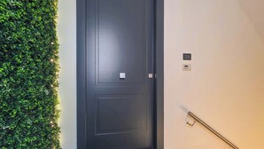 A modern hotel entrance with a dark door, a green wall, and a doormat labeled 'PERLA VERDE SUITES'. - Grigio Perla Suites  (Manfredonia)