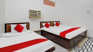 A hotel room with two beds, a small window, a wall-mounted air conditioning unit, and a tiled floor.