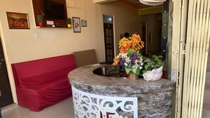 A reception area with a marble counter, a red couch, and a floral arrangement.