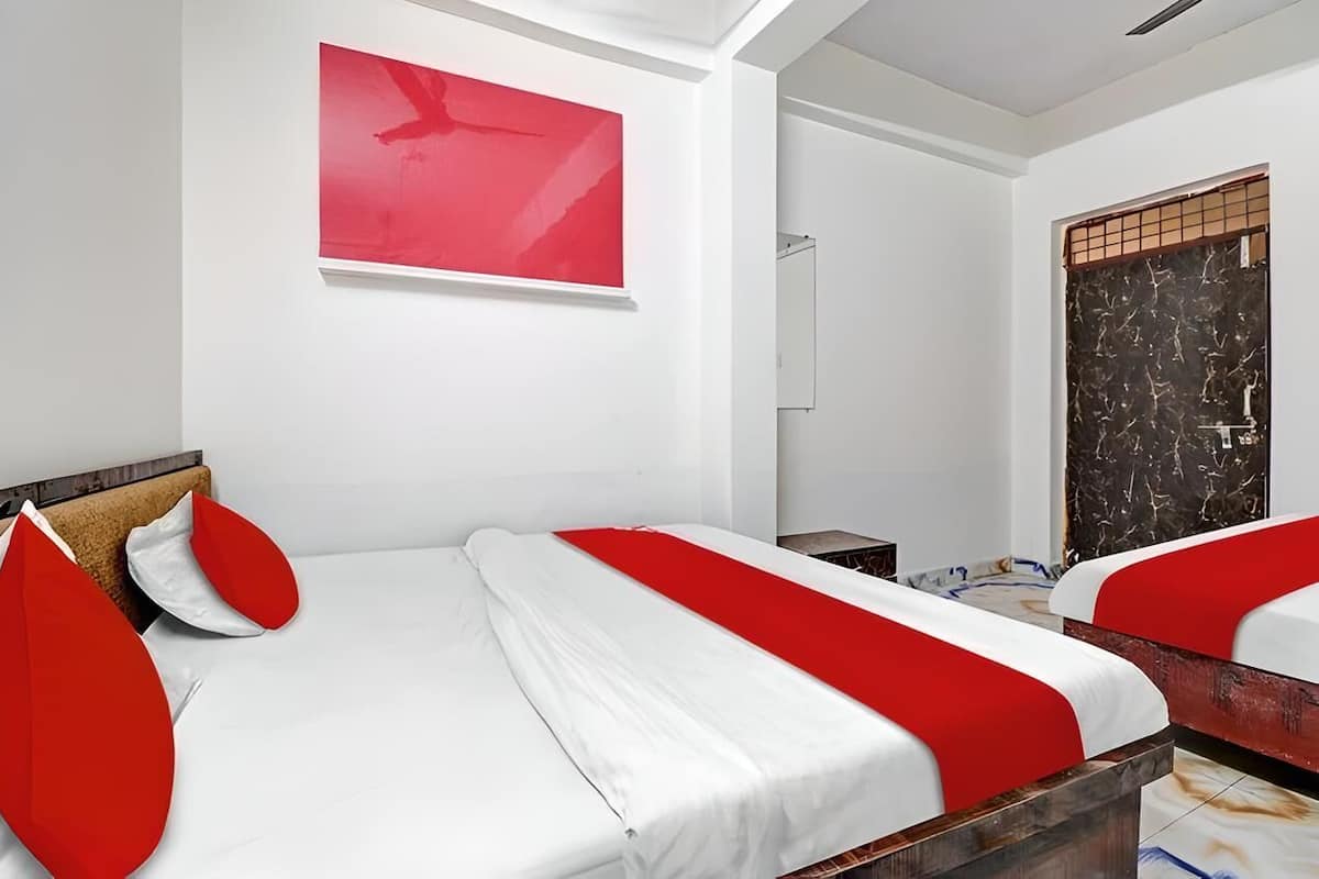 Ein Hotelzimmer mit zwei Betten, einem roten abstrakten Gemälde, einer Tür mit Marmormuster und einer weißen Decke.