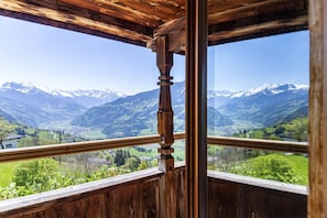 Un balcon en bois offrant une vue sur des montagnes enneigées et une vallée en contrebas.