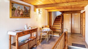 Een houten interieur met een eethoek, een trap en een schilderij aan de muur.