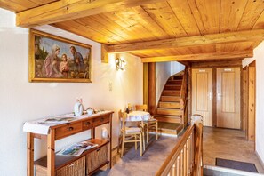 Un interior de madera con un comedor, una escalera y un cuadro en la pared.