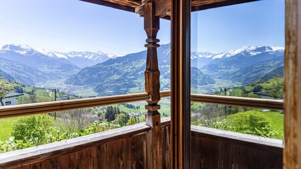 Een houten balkon met uitzicht op besneeuwde bergen en een vallei.