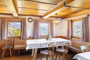 A dining area with a table, chairs, and a view of mountains.