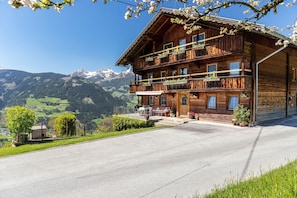 Un immeuble en bois à plusieurs étages, doté de balcons, d’une allée pavée et surplombant un paysage montagneux.