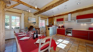 A dining area with a red tablecloth, wooden chairs, and a stone wall.