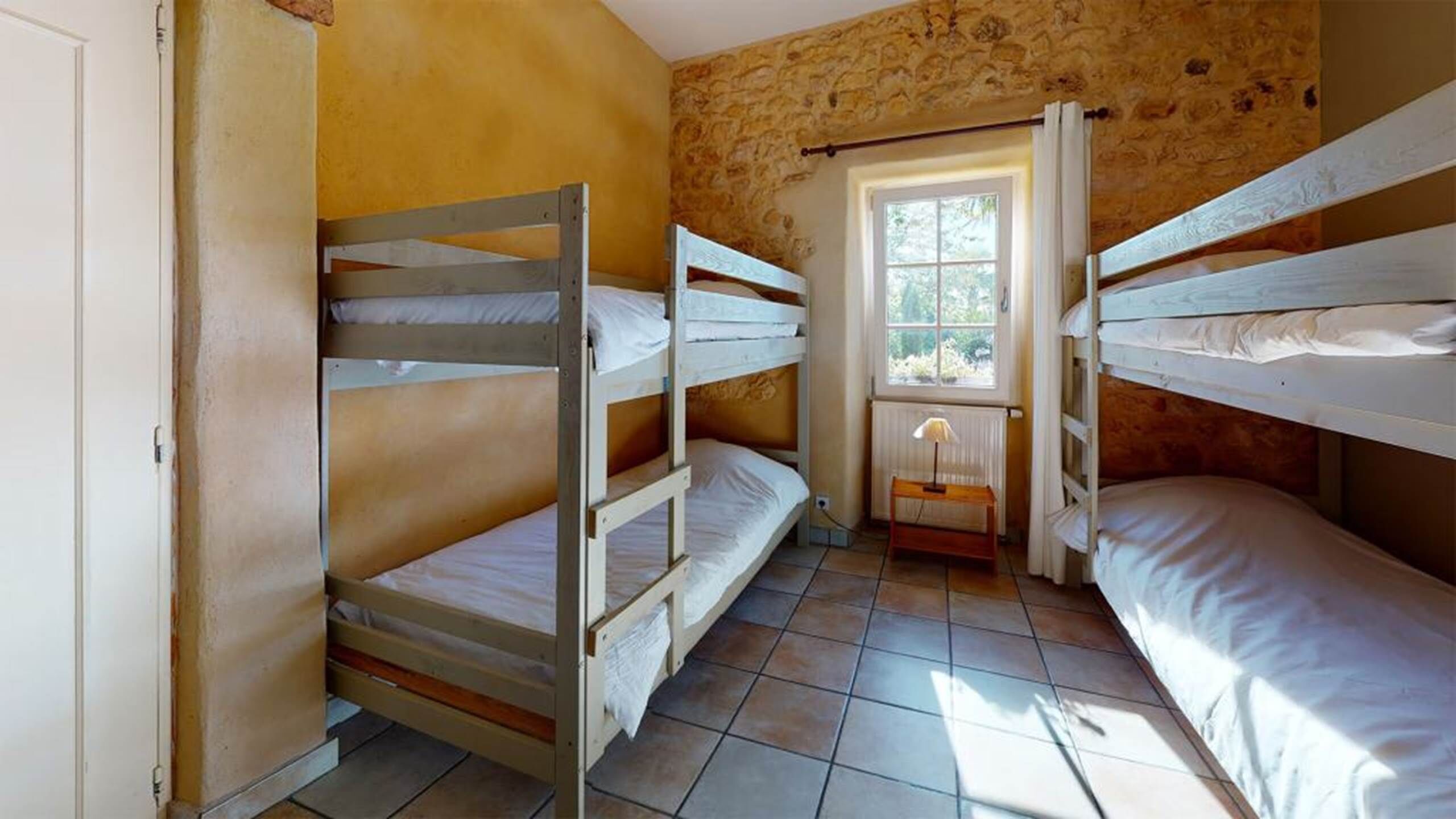 A room with bunk beds, a window, and a radiator.