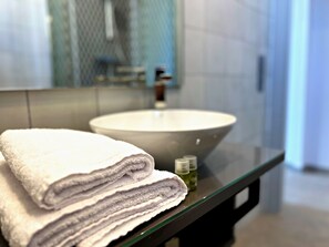 Ein Badezimmer mit einem großen Waschbecken, einem Spiegel und gestapelten Handtüchern.
