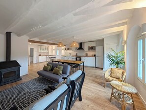 A spacious living area with a sofa, dining table, and kitchen in the background.