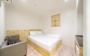A small, clean room with a wooden bed, a small desk, and a chair. - Juyeon62 (Seoul)