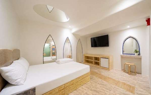 Moderni hotellihuone, jossa on suuri sänky, televisio ja puinen konsolipöytä.