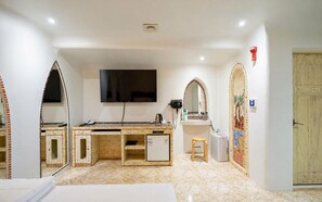 A room with a flat-screen TV mounted on the wall, a desk with a computer, a small refrigerator, a mirror, and a door with the number 405. - Juyeon62 (Seoul)
