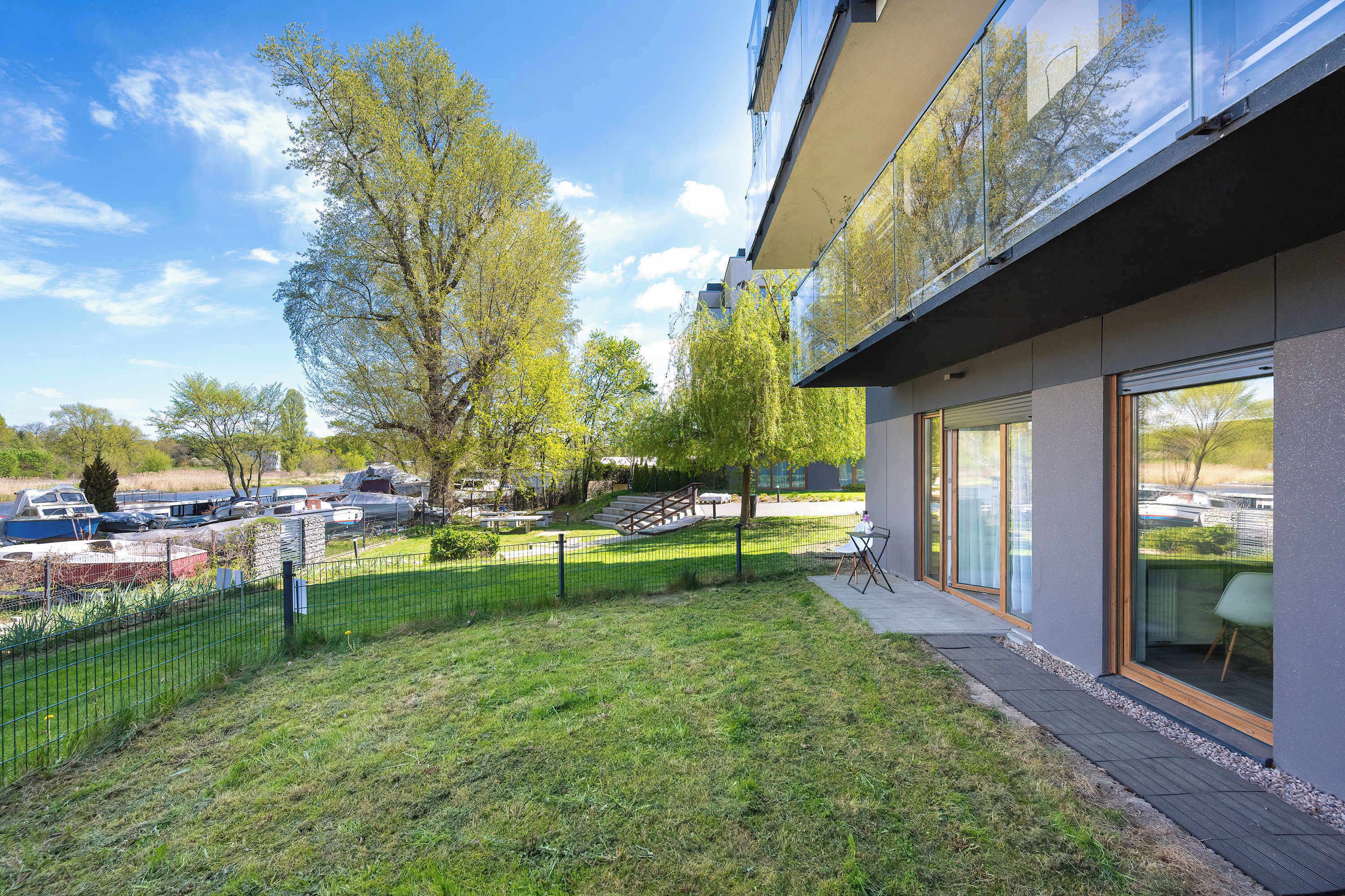 Een modern gebouw met grote ramen, een gazon en een parkeerplaats.