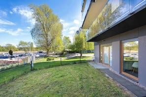 A modern building with large windows, a grassy yard, and a parking area. - Spacious Apartment | Garden and Workspace (Wrocław)