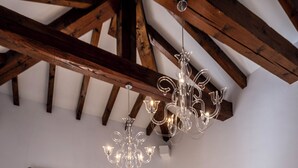 Ein Schlafzimmer mit Holzboden, einer Kristallleuchter, einem Bett mit weißer Bettwäsche und einer Balkontür.