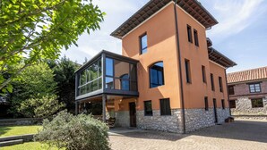 Ein modernes, zweistöckiges Gebäude mit rustikalem Steinfundament, großen Fenstern und einem Glasanbau.