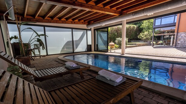 Ein Poolbereich mit Holzliegen und Blick ins Freie.