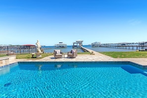 A swimming pool with lounge chairs and a statue, surrounded by a pier and a clear sky. - Coastal Cottage Retreat | Pool, Boat Dock, & Minutes to Pirates Cove (Elberta)