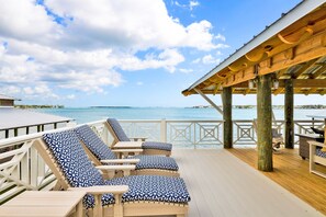 A wooden deck with lounge chairs and a covered area overlooking the sea. - Coastal Cottage Retreat | Pool, Boat Dock, & Minutes to Pirates Cove (Elberta)