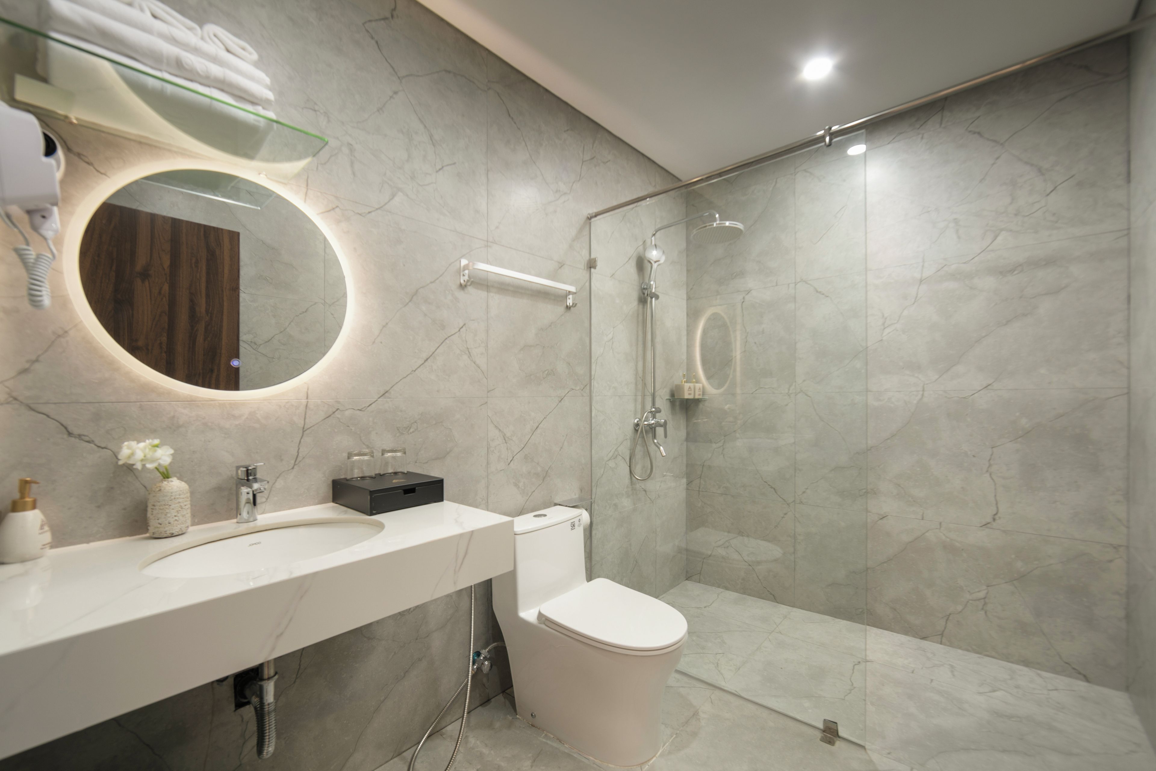 A modern bathroom with a white sink, toilet, and a glass-enclosed shower area.