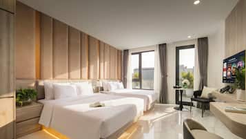 A hotel room with two beds, a desk, a chair, and a large window with curtains.