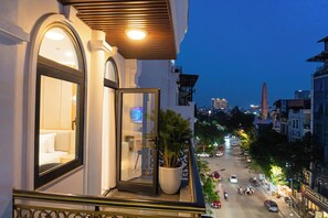 Un balcón de hotel con vista a la calle, una planta en maceta y un interior iluminado.