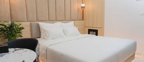 Un dormitorio moderno con una cama, mesitas de noche, una mesa redonda y una planta en maceta.