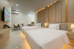 Habitación de hotel con dos camas, un escritorio, una silla y televisión montada.