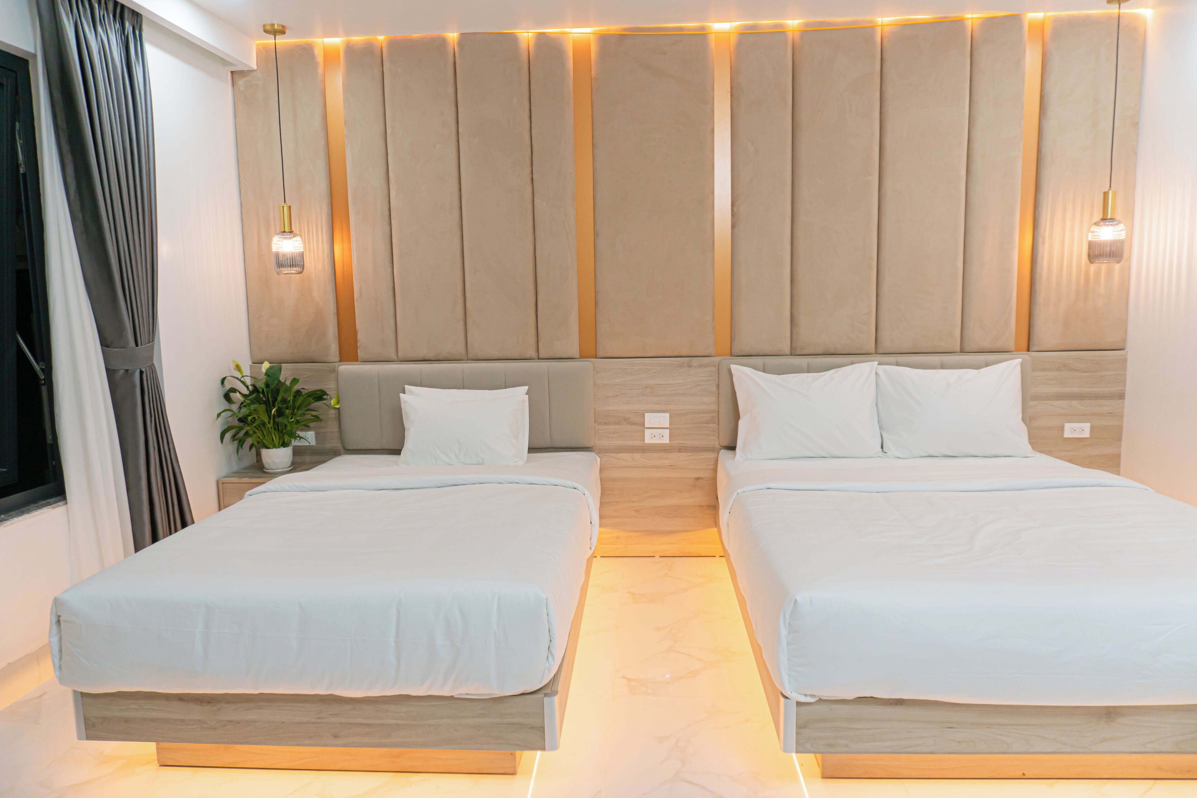 A double bed room with a wooden headboard, a potted plant, and a window with curtains.