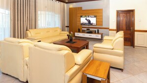 Un salon moderne avec un ensemble de canapés beige, une table basse en bois et un téléviseur à écran plat fixé au mur.