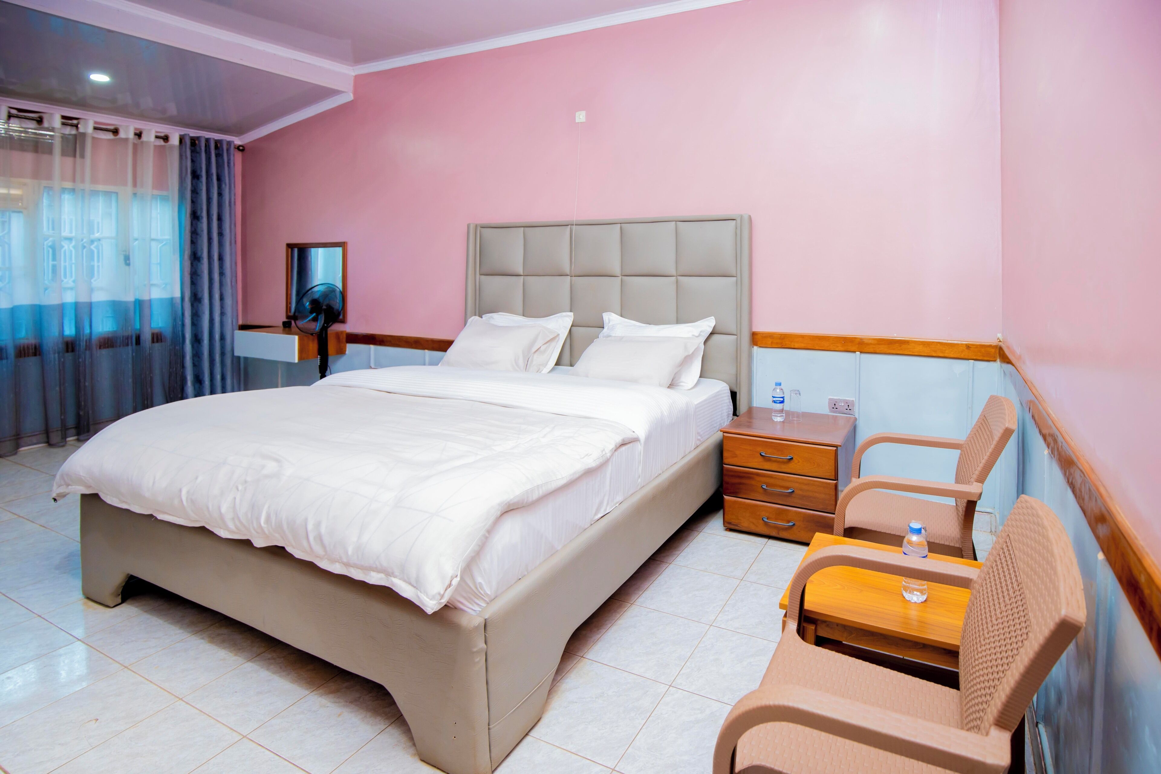 Habitación de hotel con cama, mesita de noche, silla y espejo.