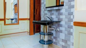 Une salle de bain avec un lavabo moderne, un miroir et un mur recouvert de carreaux.