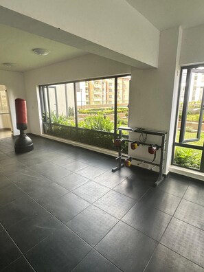A gym with exercise equipment, large windows, and a view of a residential area.