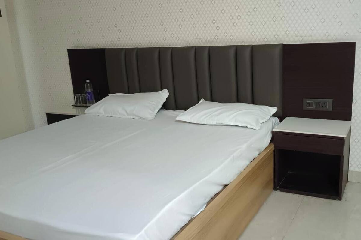 Quarto de hotel com cama, duas mesas de cabeceira, cabeceira e parede com padrão.
