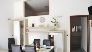 A modern kitchen with a dining area, a clock, and a plant on the wall. - Marylu' Holiday Home in Torre Specchia (Torre Specchia Ruggeri)